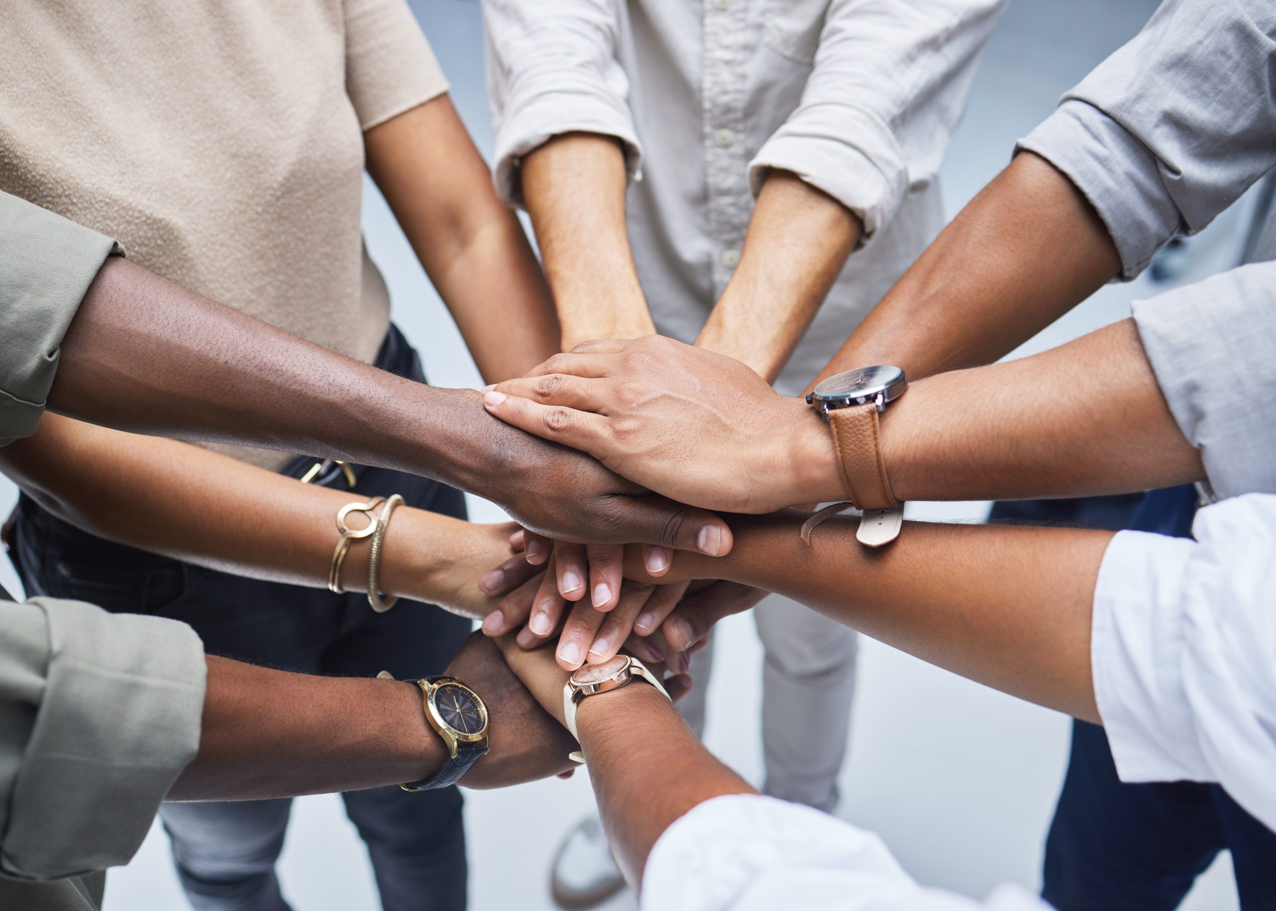 High angle shot of a group of unrecognisable businesspeople joining their hands together in a huddle